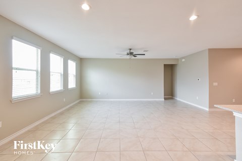 A spacious room with a ceiling fan and a table in the corner.