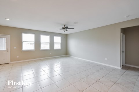 A spacious room with a fan and tile flooring.