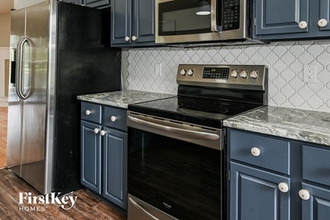 A kitchen with a black refrigerator and stove top oven.
