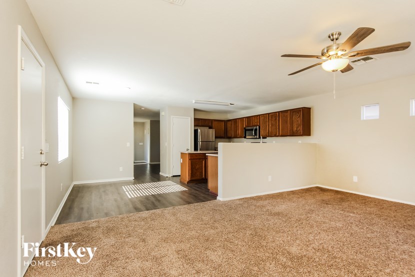 A spacious living room with a carpeted floor and a ceiling fan.