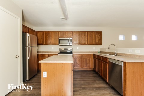 A kitchen with wooden cabinets and a stainless steel refrigerator.