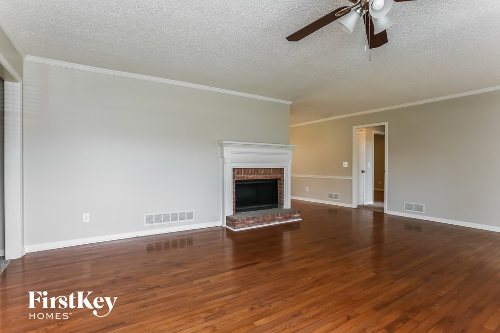 the living room with wood floors and a fireplace