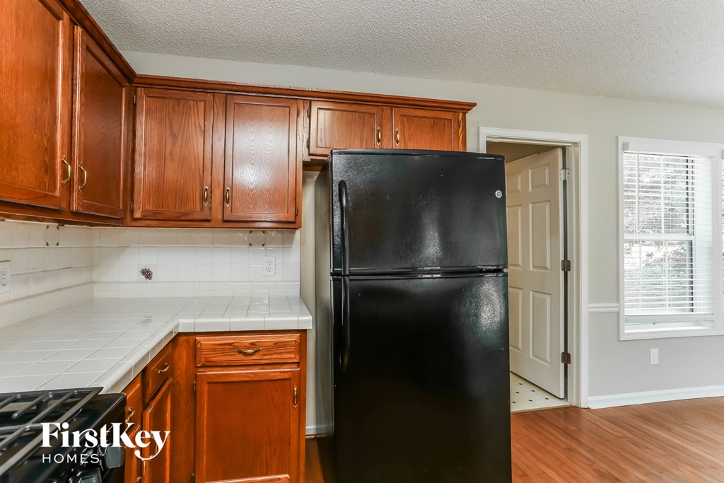 a kitchen with a black refrigerator and wooden cabinets