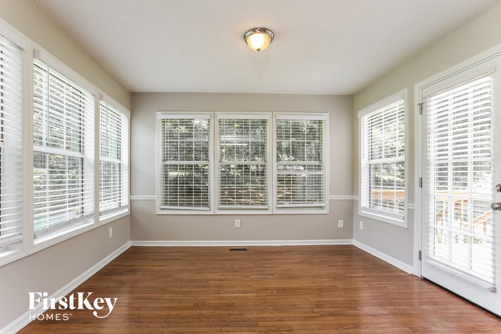 an empty living room with large windows and wood flooring