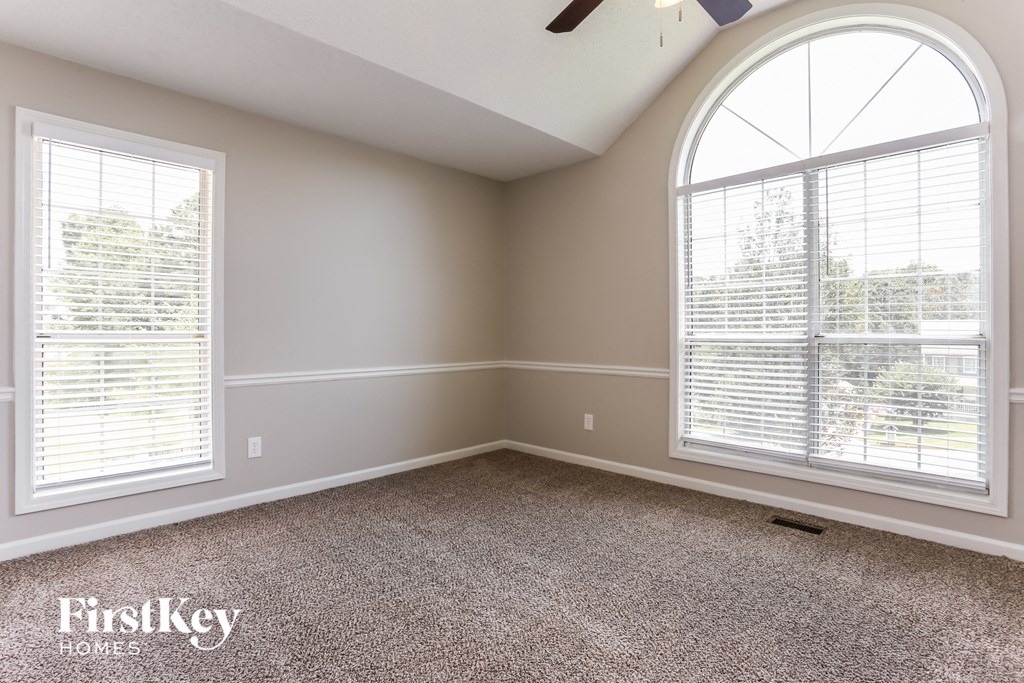 a bedroom with two large windows and a carpeted floor