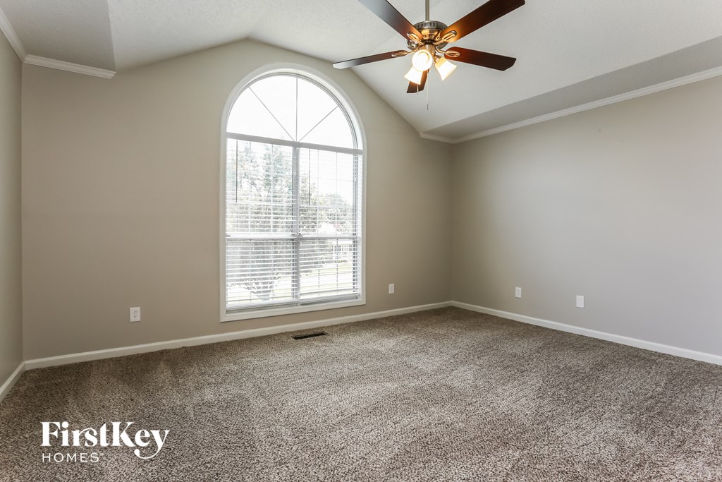 an empty living room with a large window and a ceiling fan