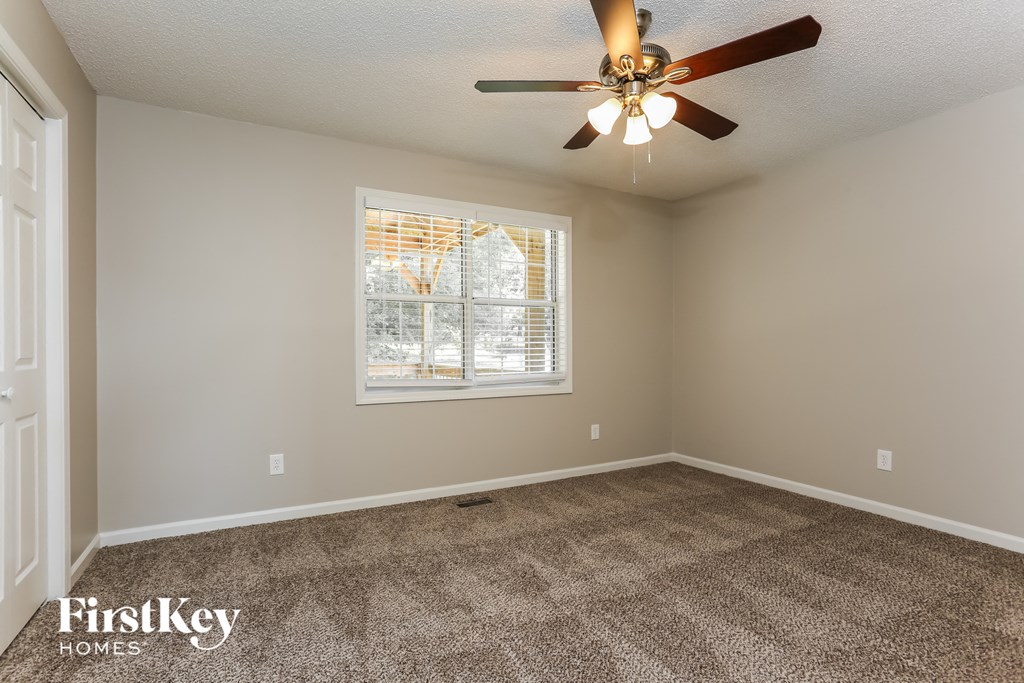 the master bedroom is spacious and has carpeted floors and a ceiling fan