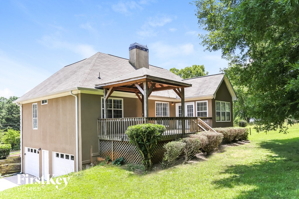 a small brown house with a porch and a fence