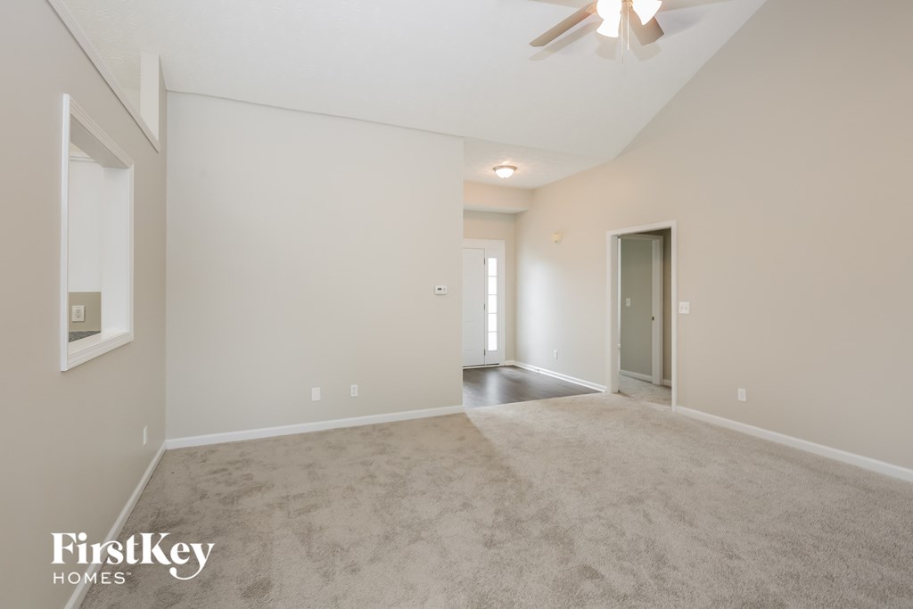 a spacious living room with carpet and a ceiling fan
