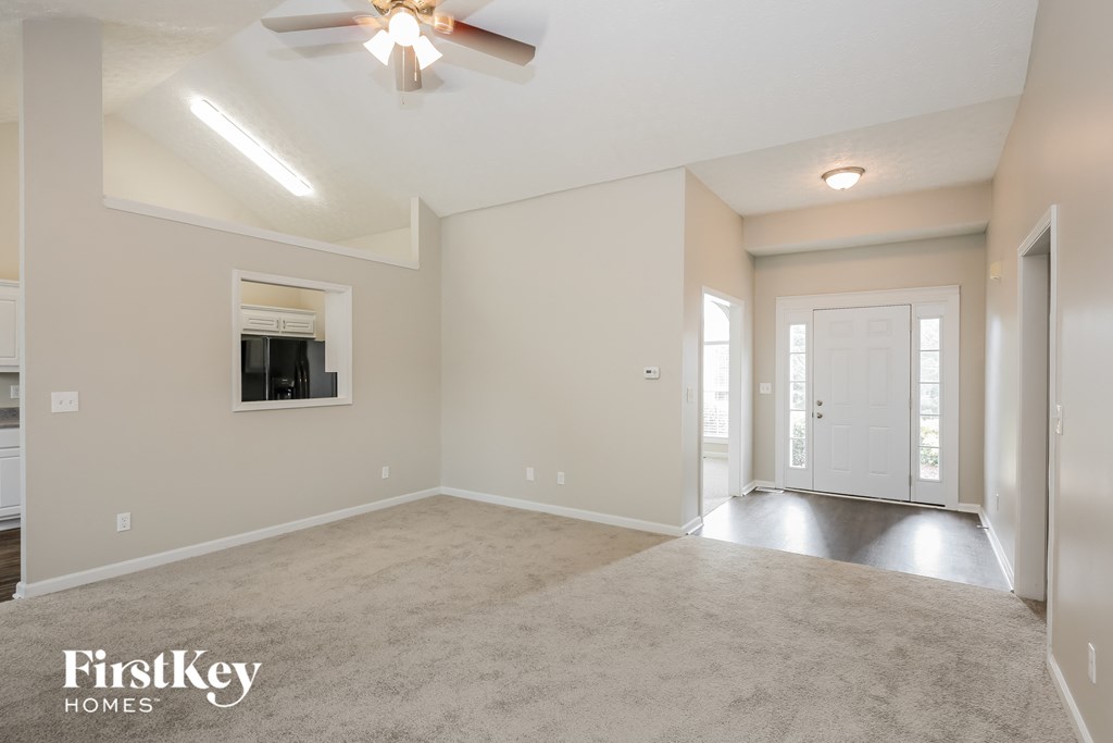 an empty living room with a ceiling fan