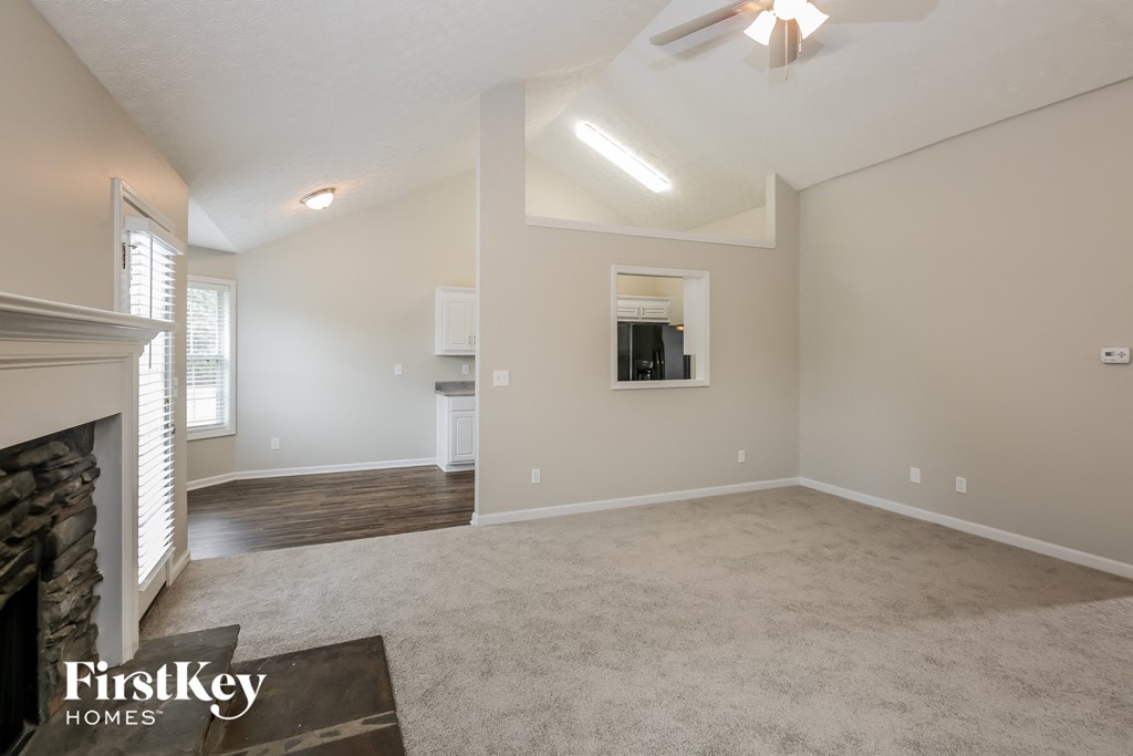 an empty living room with a fireplace and a ceiling fan