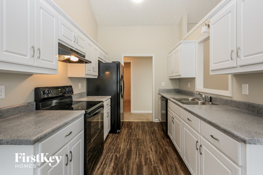 a kitchen with white cabinets and black appliances and a wood floor