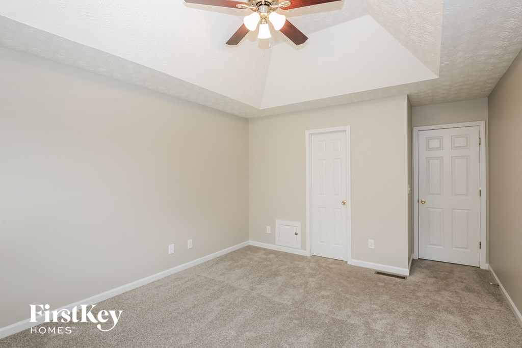 the master bedroom has a carpeted floor and a ceiling fan