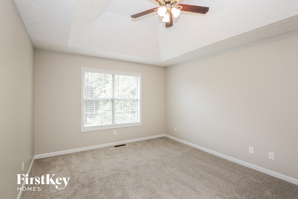 an empty room with a ceiling fan and a window