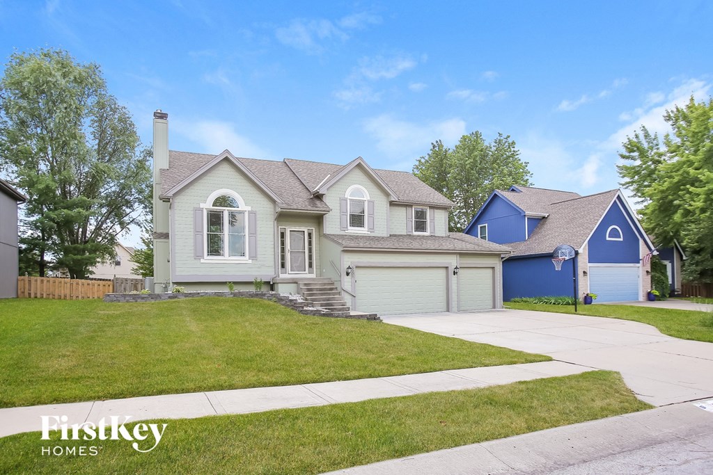 a blue and white house with a lawn and a driveway