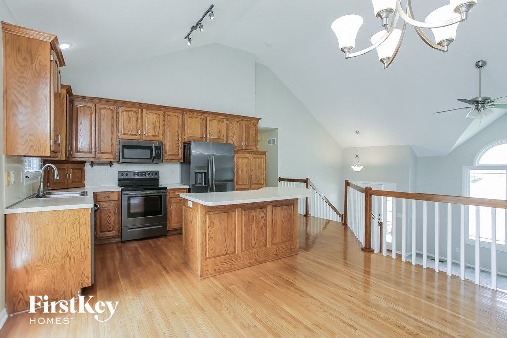 a kitchen with wood floors and wooden cabinets and a staircase