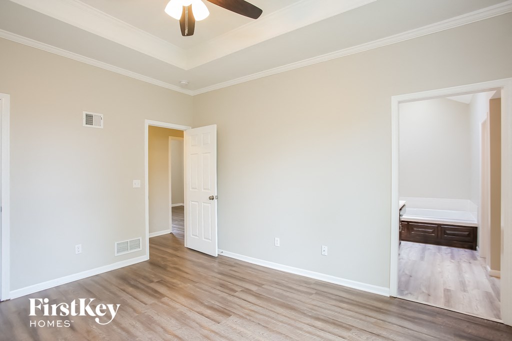 a bedroom with white walls and wood flooring and a ceiling fan