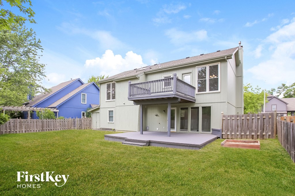 a white house with a deck and a yard and a blue house