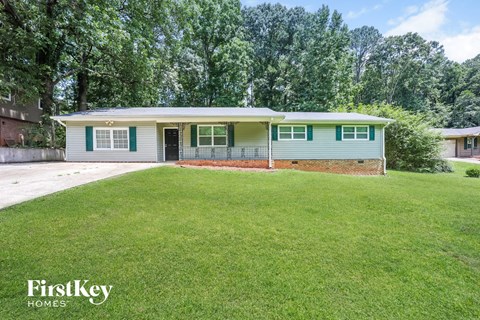 a blue and green house with a lawn and a driveway
