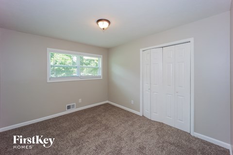 a bedroom with carpet and a white door and window