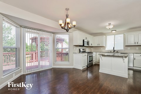 a kitchen with white cabinets and wood floors and a large window