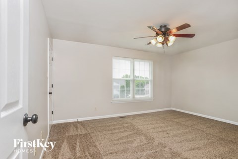 a living room with carpet and a ceiling fan