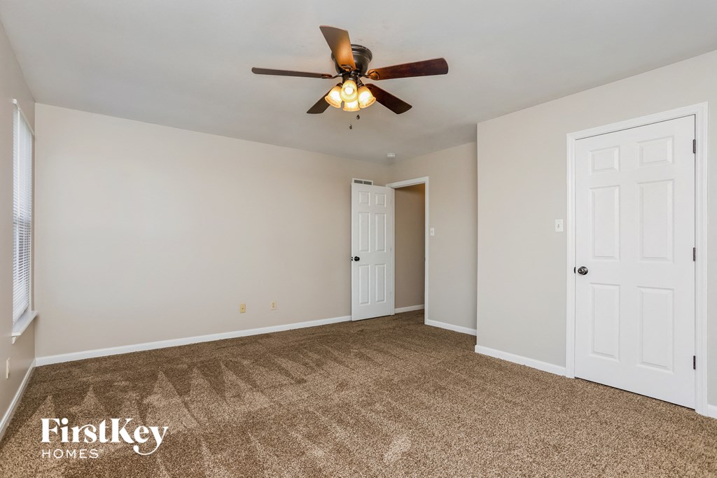 an empty living room with a ceiling fan and a closet