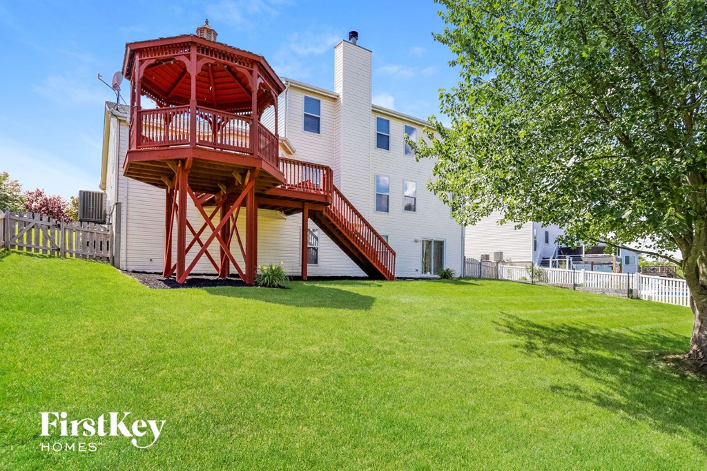 a home with a red and white deck on top of a green yard