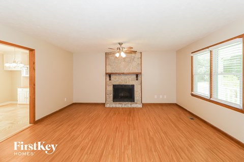 A spacious living room with a fireplace and wooden floors.