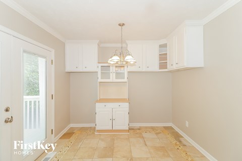 A kitchen with white cabinets and a tan floor.