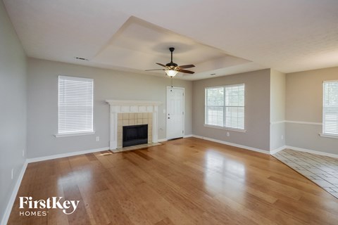 an empty living room with a fireplace and a ceiling fan