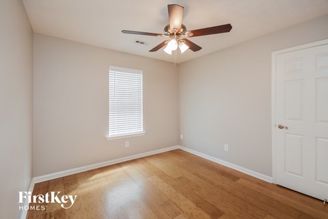 a bedroom with wood floors and a ceiling fan