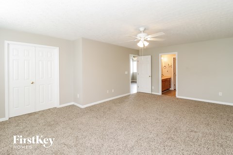 a spacious living room with carpet and a ceiling fan