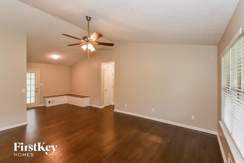 an empty living room with wood floors and a ceiling fan