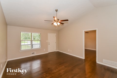 an empty living room with wood floors and a ceiling fan