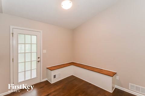 a bedroom with white walls and wood flooring and a window