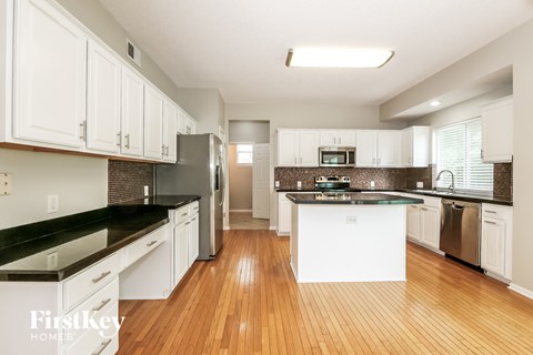 A kitchen with white cabinets and a black counter top.