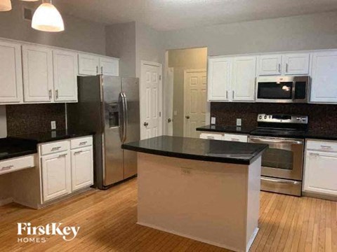 A kitchen with white cabinets and a black countertop.