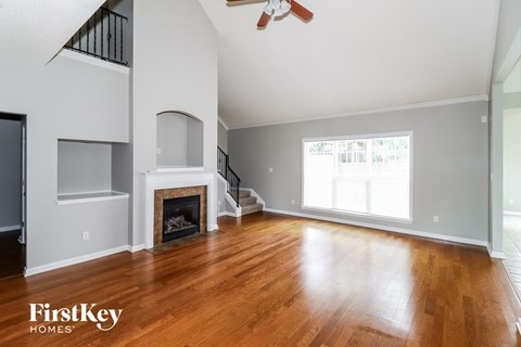 A spacious living room with a fireplace and wooden floors.