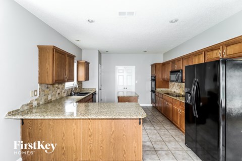 A kitchen with wooden cabinets and a black refrigerator.