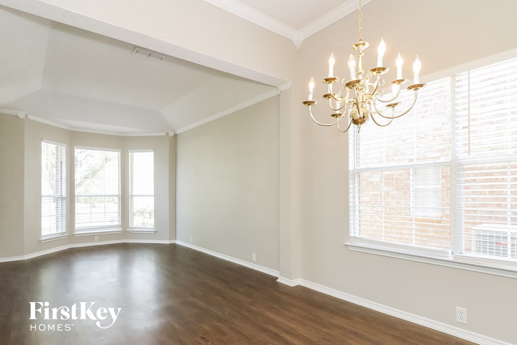 A room with a chandelier and a window with blinds.
