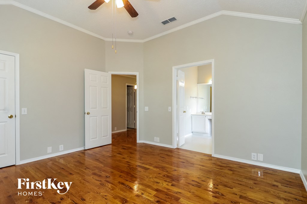 A spacious room with wooden floors and a ceiling fan.