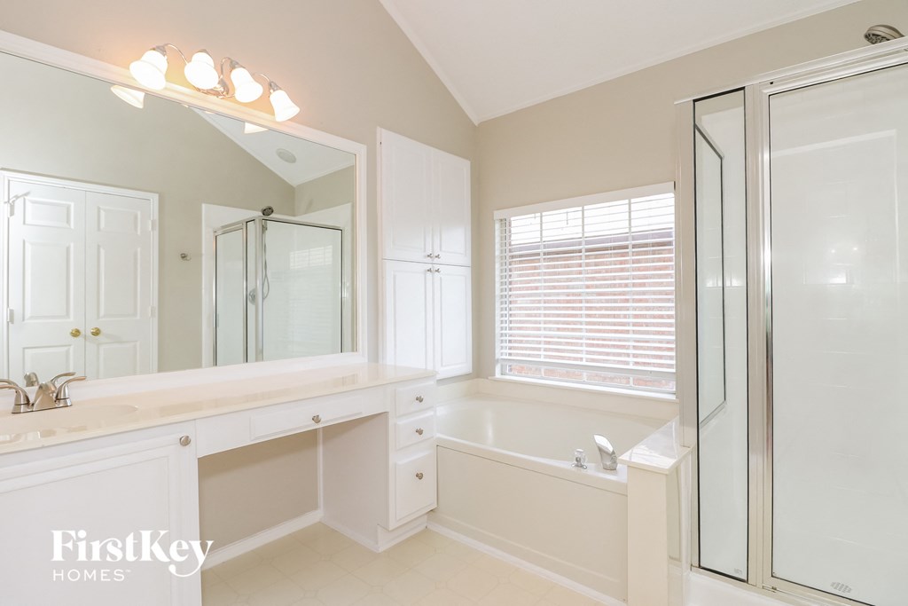 A white bathroom with a large mirror and a walk-in shower.
