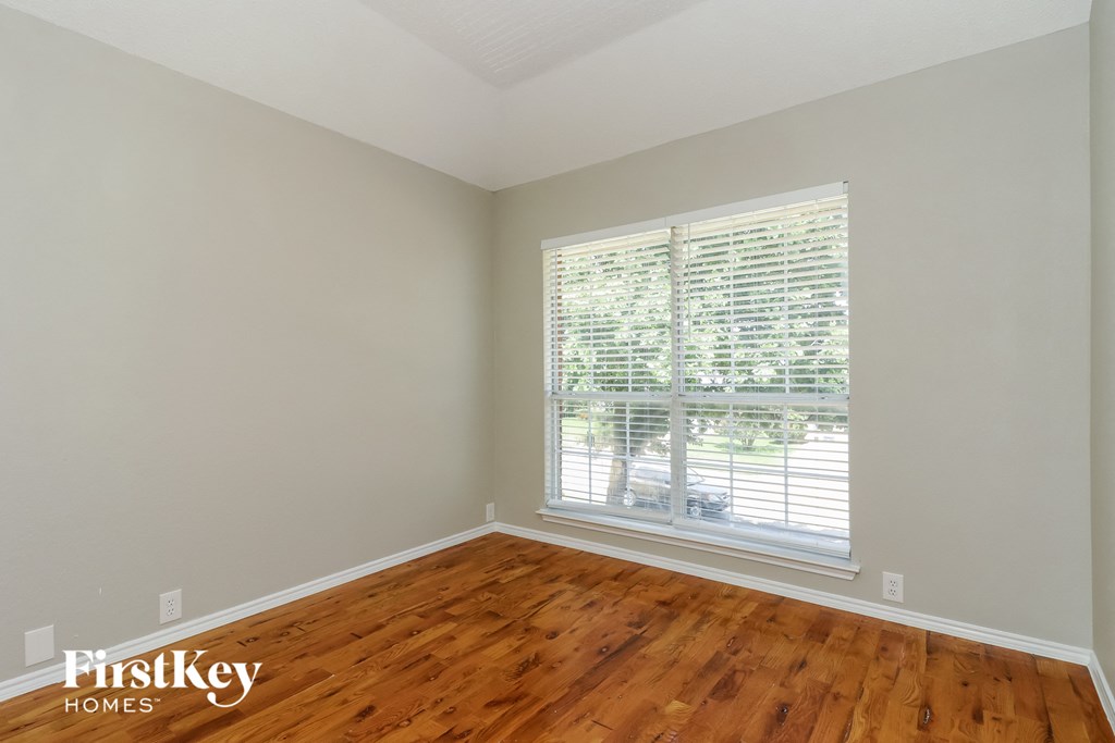 A room with wooden floors and a window with blinds.