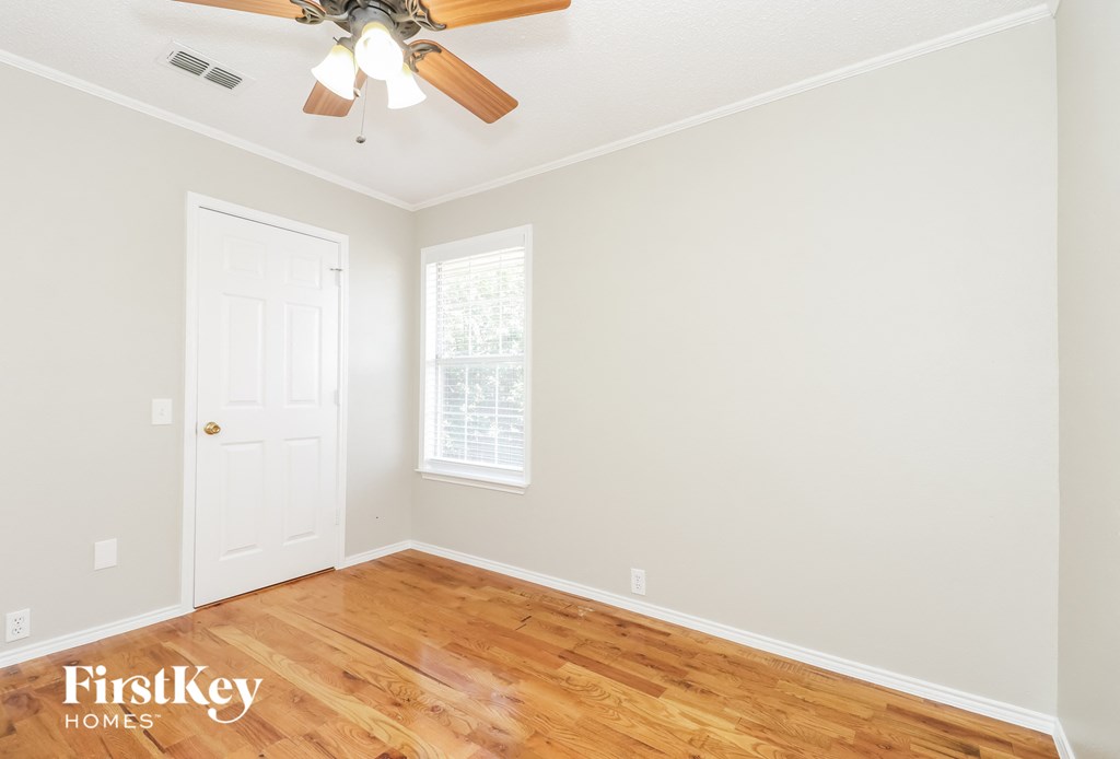 A room with a ceiling fan and wooden floors.