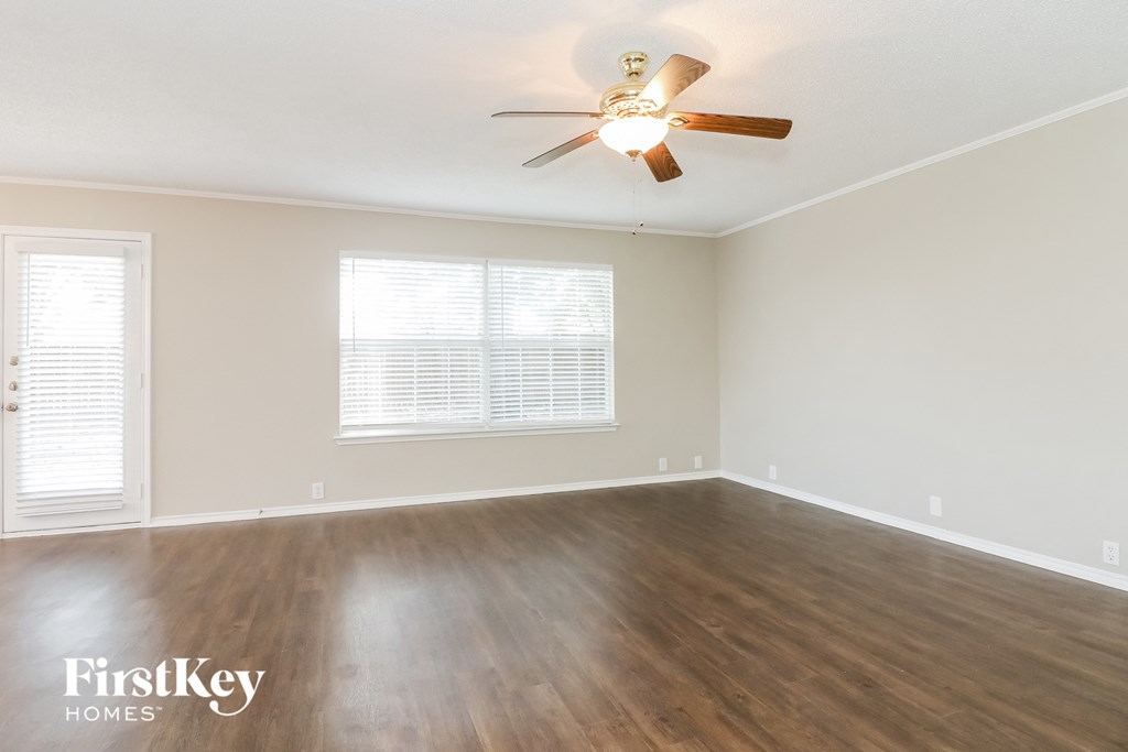 A room with a ceiling fan and wooden flooring.