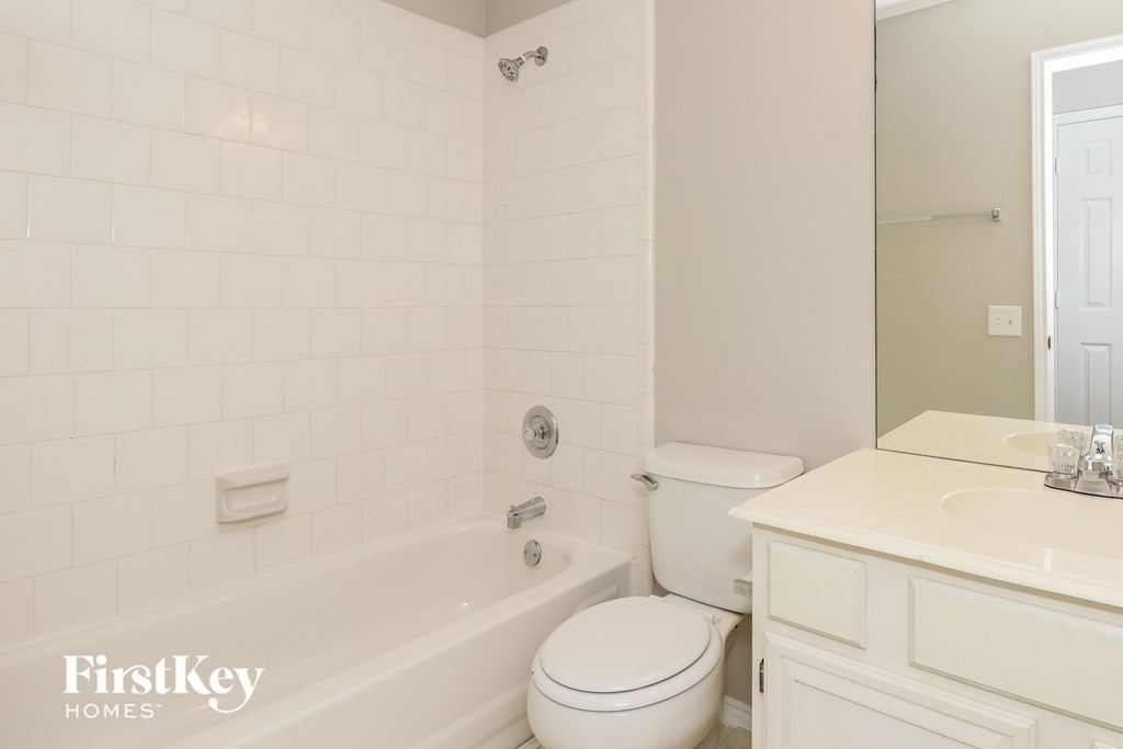 A white bathroom with a tub, toilet and sink.