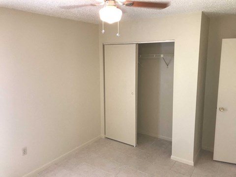 an empty bedroom with a closet and a ceiling fan