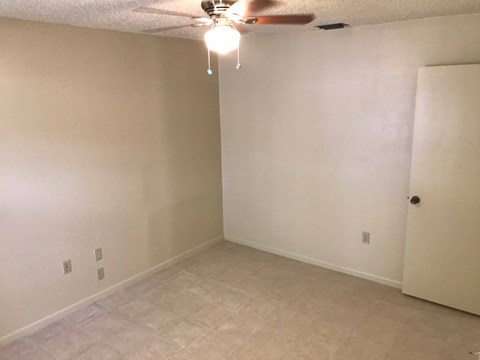 a living room with white walls and a ceiling fan