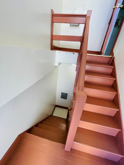 A brown wooden staircase with a white wall on the side.